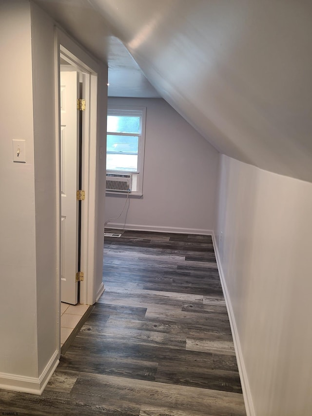 additional living space featuring cooling unit, dark wood-type flooring, and vaulted ceiling