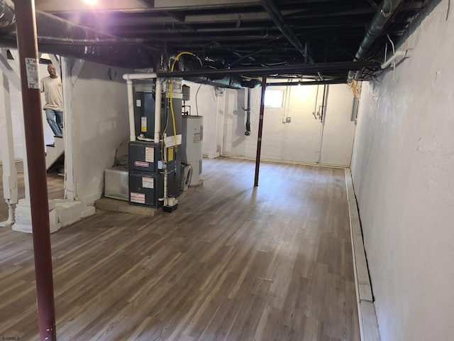 basement featuring wood-type flooring, heating unit, and water heater