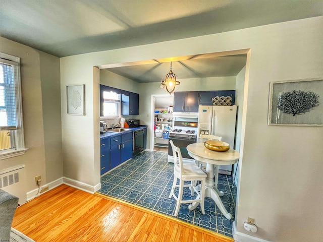 kitchen with blue cabinetry, white appliances, radiator heating unit, dark hardwood / wood-style flooring, and hanging light fixtures