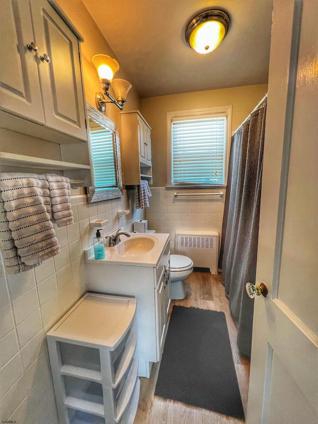 bathroom featuring vanity, tasteful backsplash, toilet, hardwood / wood-style flooring, and radiator heating unit