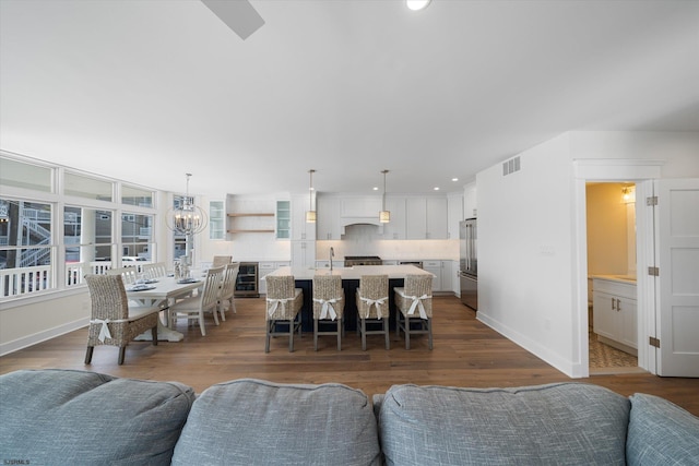 living room featuring dark wood-type flooring, an inviting chandelier, and wine cooler