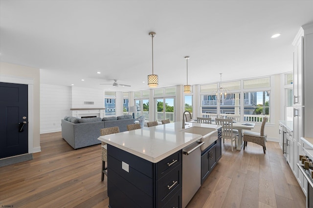 kitchen featuring ceiling fan, plenty of natural light, wood-type flooring, and a kitchen island with sink