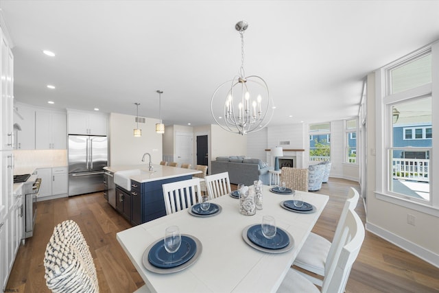 dining area with wood-type flooring, an inviting chandelier, and sink