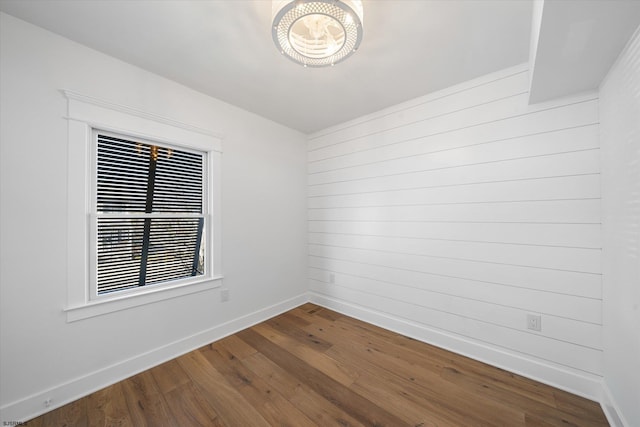 spare room with hardwood / wood-style flooring and wood walls