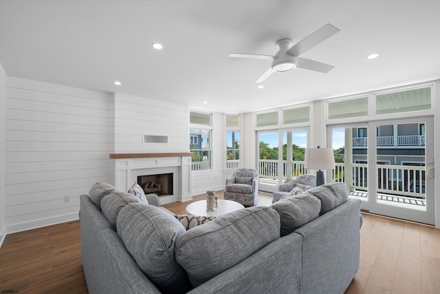 living room with hardwood / wood-style floors, wood walls, and ceiling fan