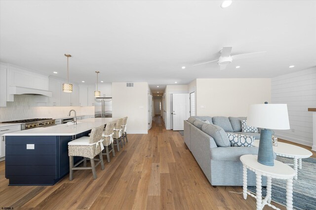 living room featuring ceiling fan, sink, and light wood-type flooring