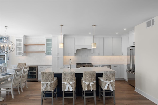 kitchen with appliances with stainless steel finishes, beverage cooler, an inviting chandelier, and an island with sink