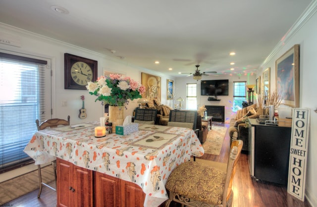 dining area with dark wood-type flooring, ceiling fan, and ornamental molding