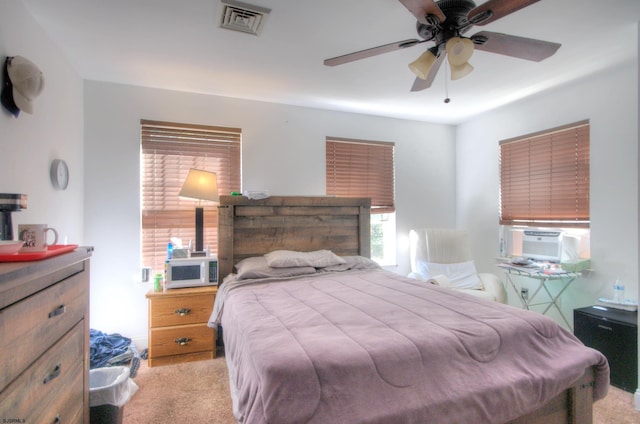 bedroom featuring cooling unit, light colored carpet, and ceiling fan