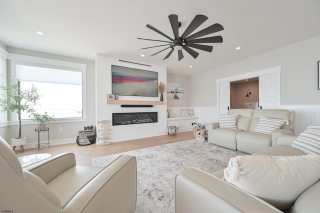 living room with a large fireplace, ceiling fan, and hardwood / wood-style flooring