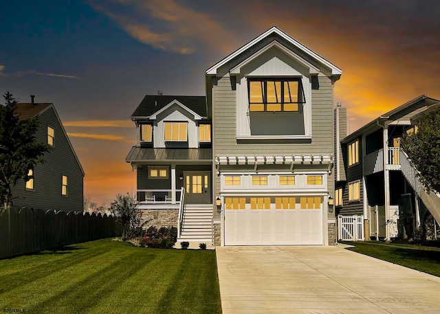 view of front of house with a garage, covered porch, and a lawn