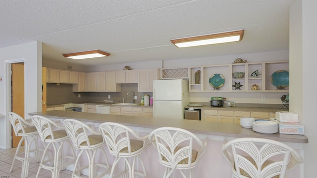 kitchen with light tile patterned floors, sink, a kitchen bar, and white appliances