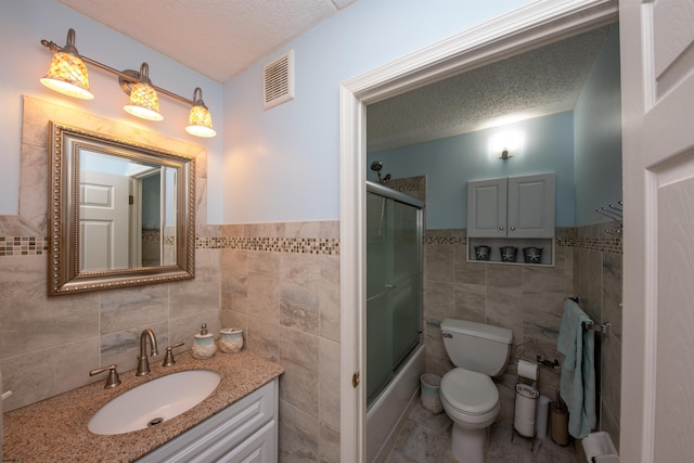 full bathroom featuring tile walls, a textured ceiling, vanity, and toilet