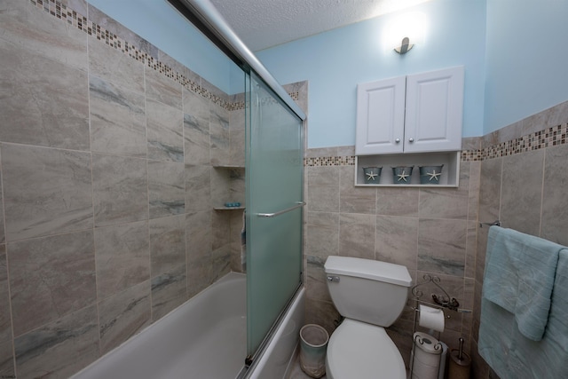 bathroom featuring tile walls, toilet, a textured ceiling, and bath / shower combo with glass door