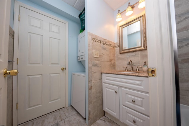 bathroom with vanity, tile walls, and stacked washing maching and dryer