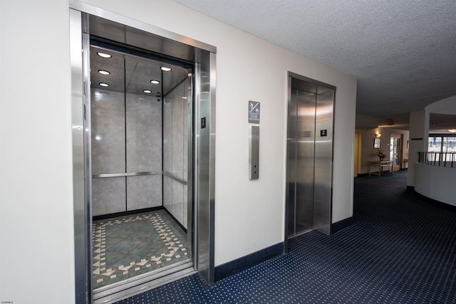 hall featuring a textured ceiling and elevator