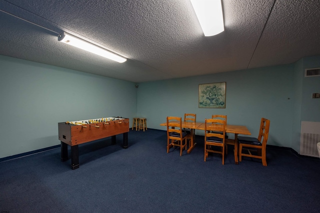 recreation room with dark carpet and a textured ceiling