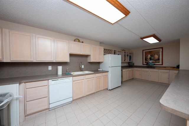 kitchen featuring a textured ceiling, kitchen peninsula, sink, and white appliances