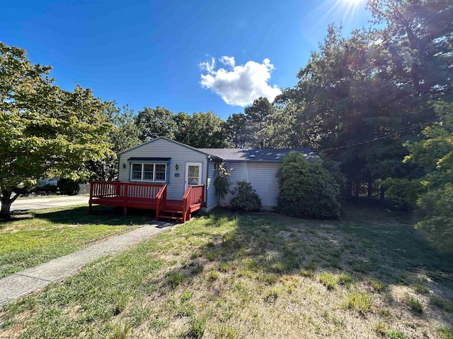 single story home featuring a front yard and a wooden deck