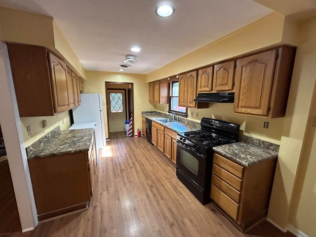 kitchen with black appliances, sink, and light wood-type flooring