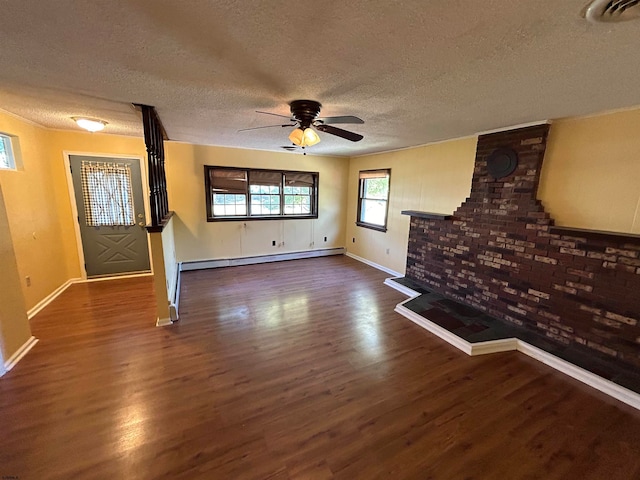 unfurnished living room featuring baseboard heating, ceiling fan, dark hardwood / wood-style floors, and a textured ceiling