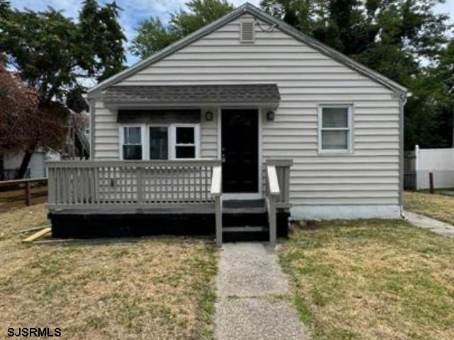 bungalow with a front yard and a deck