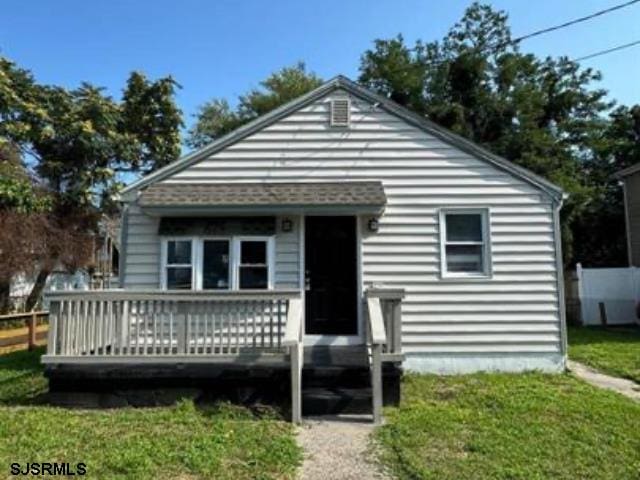 bungalow-style house with a deck and a front lawn