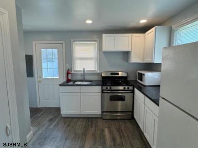 kitchen with white appliances, a healthy amount of sunlight, and white cabinets