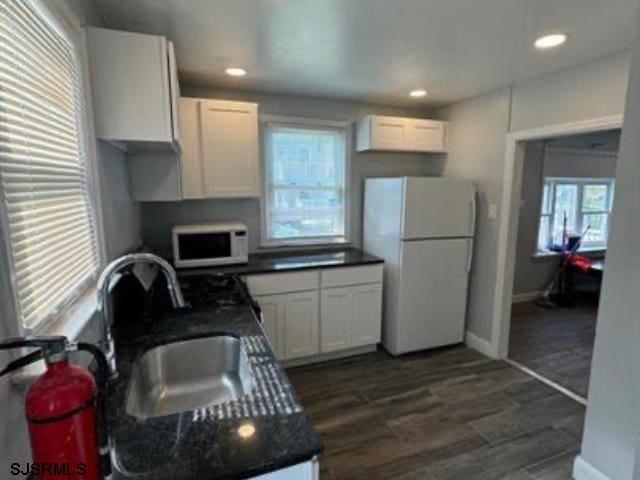 kitchen with dark wood-type flooring, white cabinets, white appliances, and sink