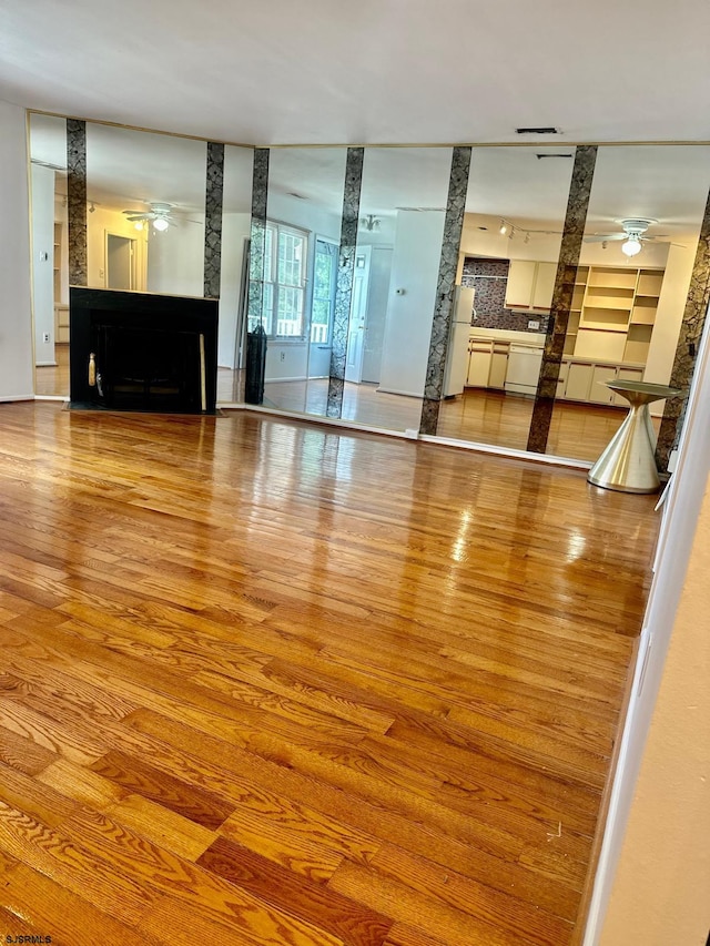 unfurnished living room with a large fireplace, ceiling fan, and hardwood / wood-style floors