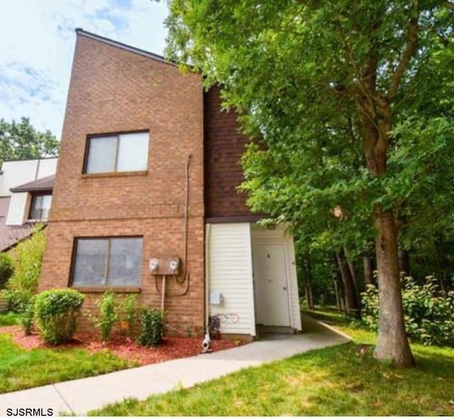 rear view of house featuring brick siding and a yard