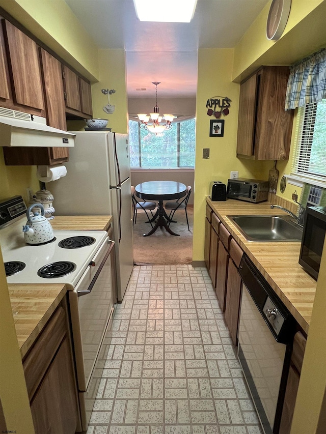 kitchen with black appliances, sink, a notable chandelier, and hanging light fixtures