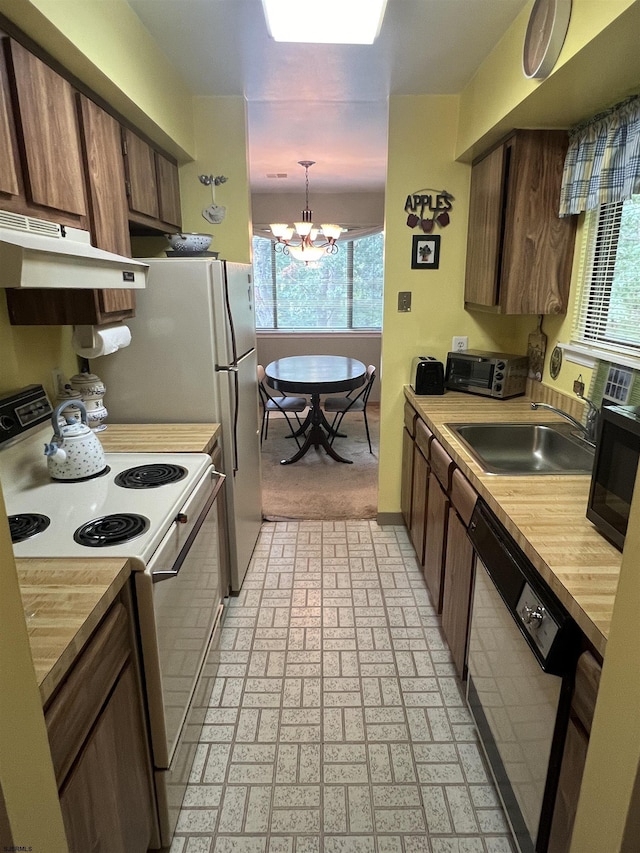 kitchen with under cabinet range hood, a sink, white range with electric stovetop, an inviting chandelier, and dishwashing machine