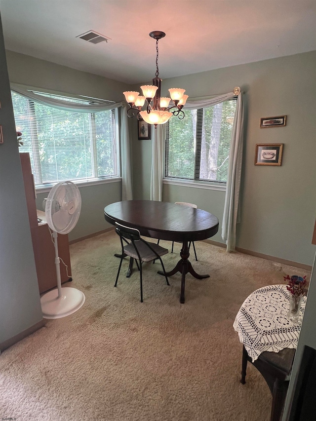 carpeted dining area with a chandelier