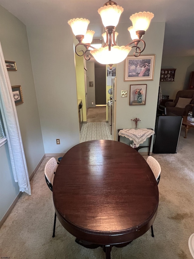 dining room featuring an inviting chandelier, light colored carpet, and baseboards