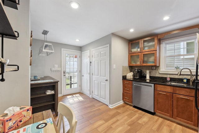 kitchen featuring pendant lighting, dishwasher, sink, dark stone countertops, and light wood-type flooring