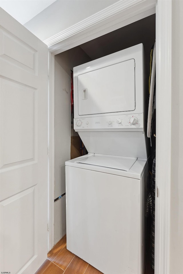 laundry area with stacked washing maching and dryer and light hardwood / wood-style floors