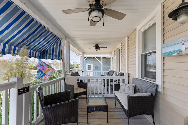 wooden terrace with an outdoor living space, covered porch, and ceiling fan