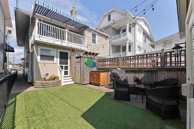 rear view of house with a lawn, an outdoor living space, a patio area, and a balcony