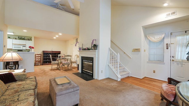 living room featuring high vaulted ceiling, light hardwood / wood-style flooring, and ceiling fan