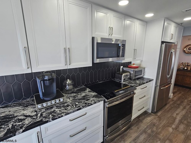 kitchen featuring dark wood-type flooring, appliances with stainless steel finishes, decorative backsplash, and white cabinetry