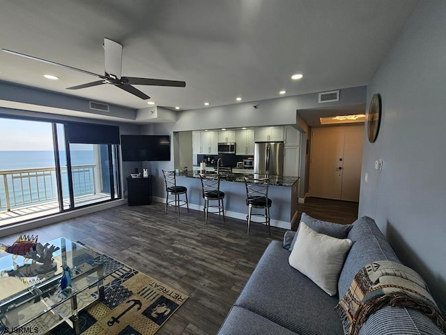 living room with a water view, ceiling fan, and dark hardwood / wood-style floors