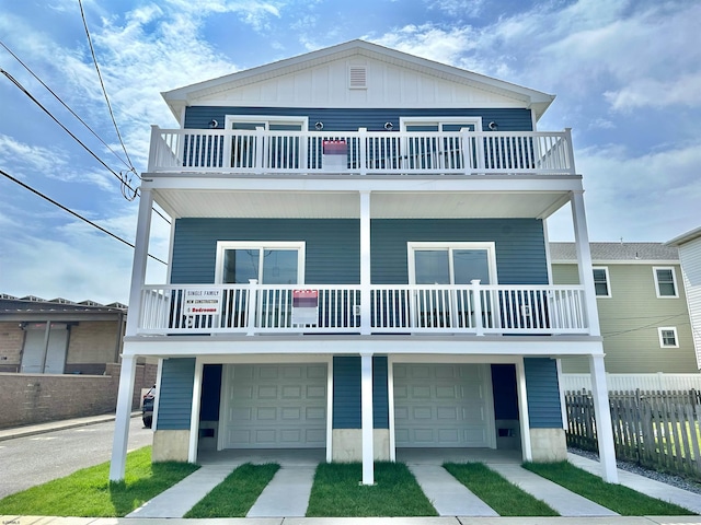 view of property featuring driveway, fence, board and batten siding, a garage, and a balcony