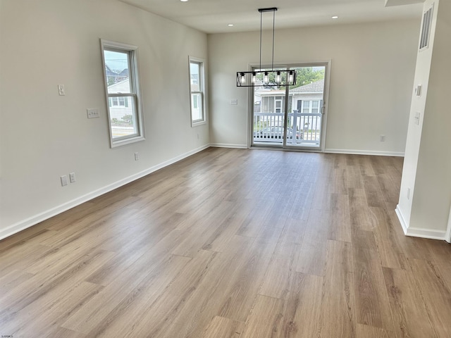 unfurnished dining area featuring a wealth of natural light, a chandelier, baseboards, and wood finished floors