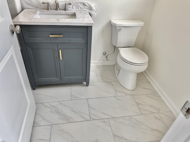 bathroom featuring baseboards, toilet, marble finish floor, and vanity