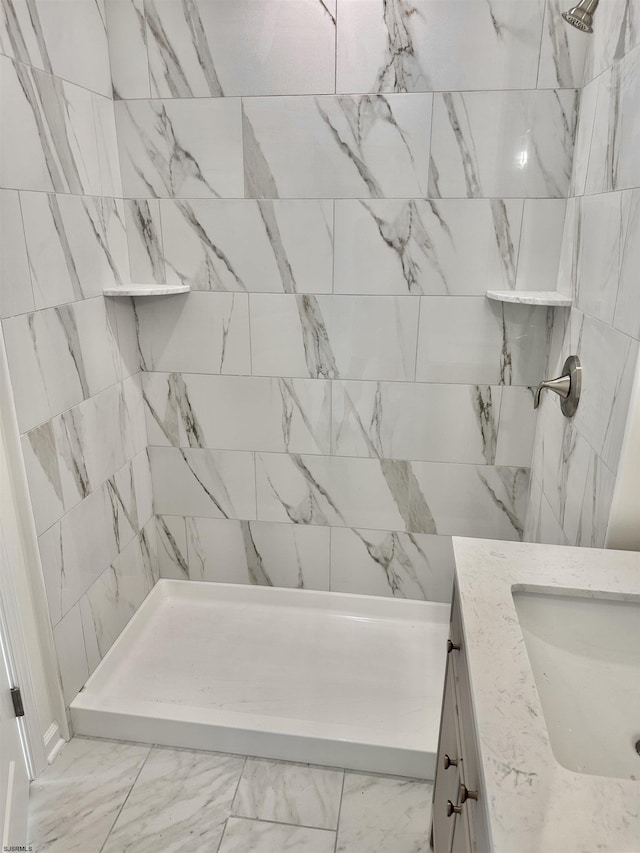 bathroom featuring tiled shower, marble finish floor, and vanity