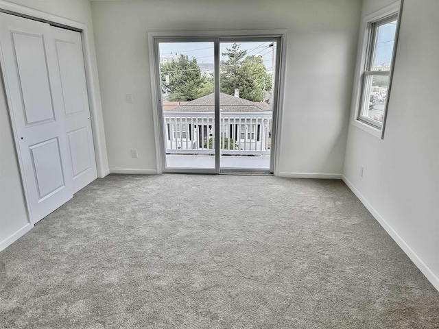 unfurnished bedroom featuring multiple windows, baseboards, carpet, and access to outside