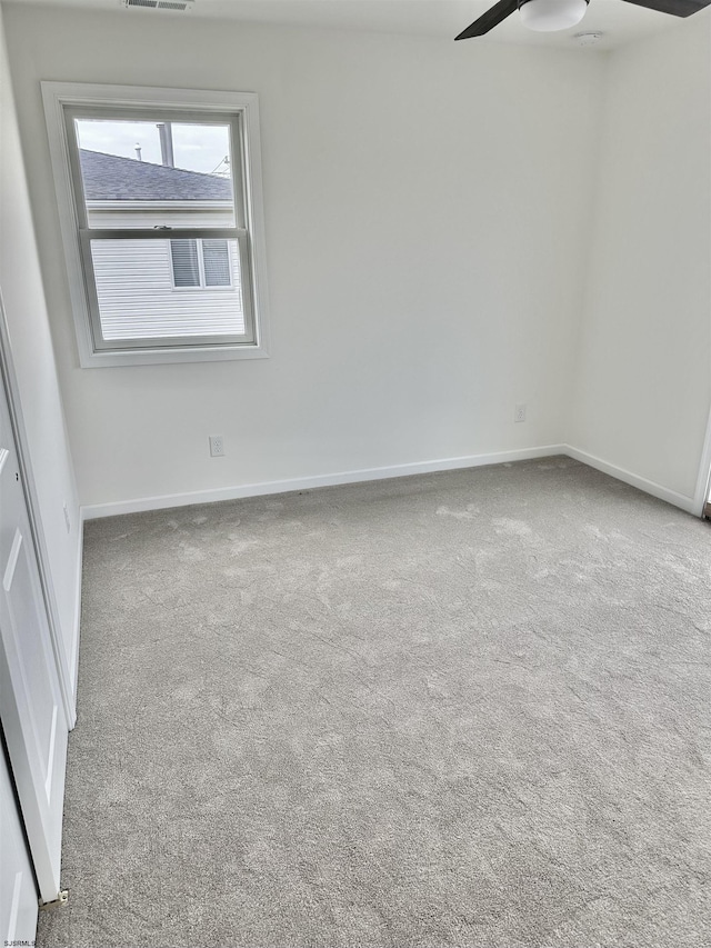 carpeted spare room with a ceiling fan, visible vents, and baseboards