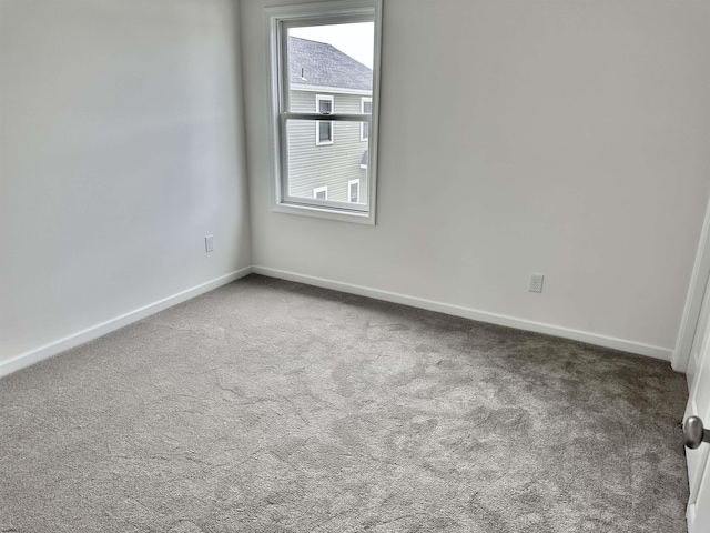 carpeted spare room featuring baseboards