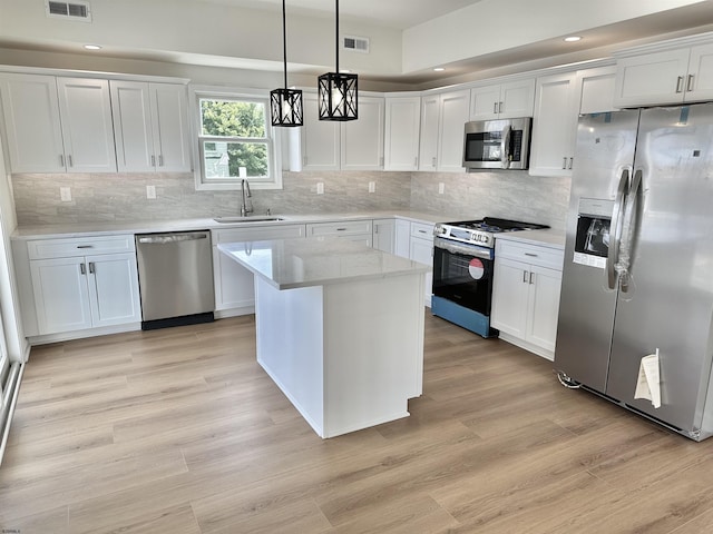 kitchen with a sink, light wood-style flooring, white cabinetry, and stainless steel appliances